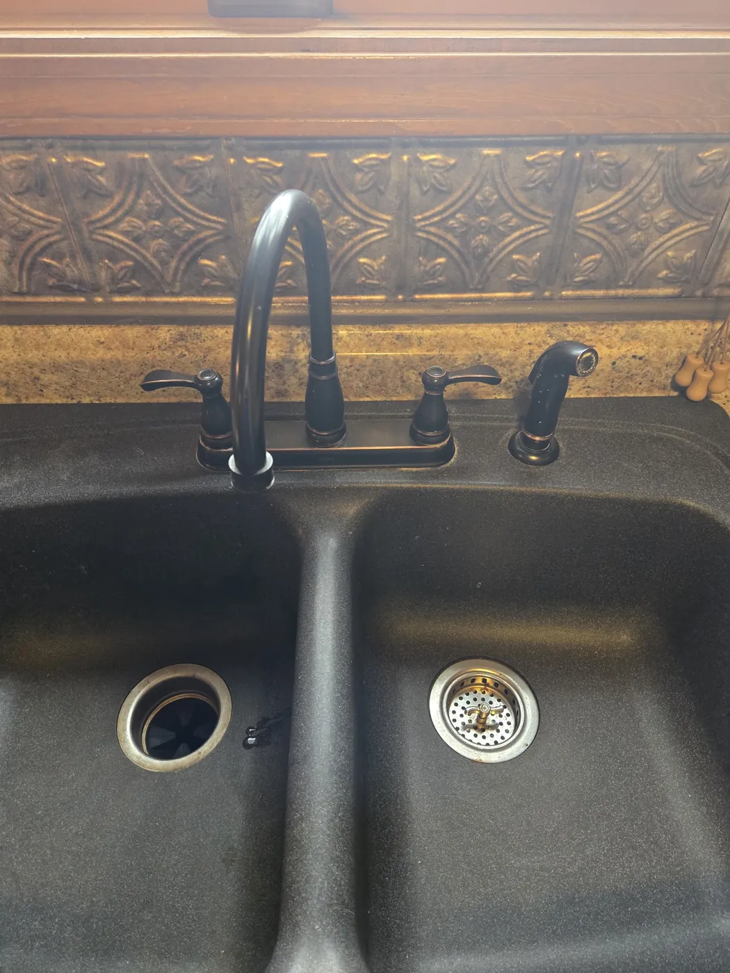 New bronze kitchen faucet installed on a double-basin sink