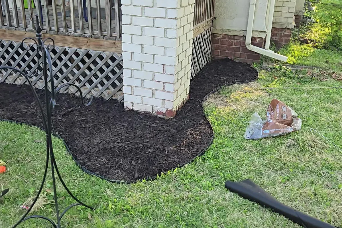 Fresh mulch bed edged around a porch and brick column