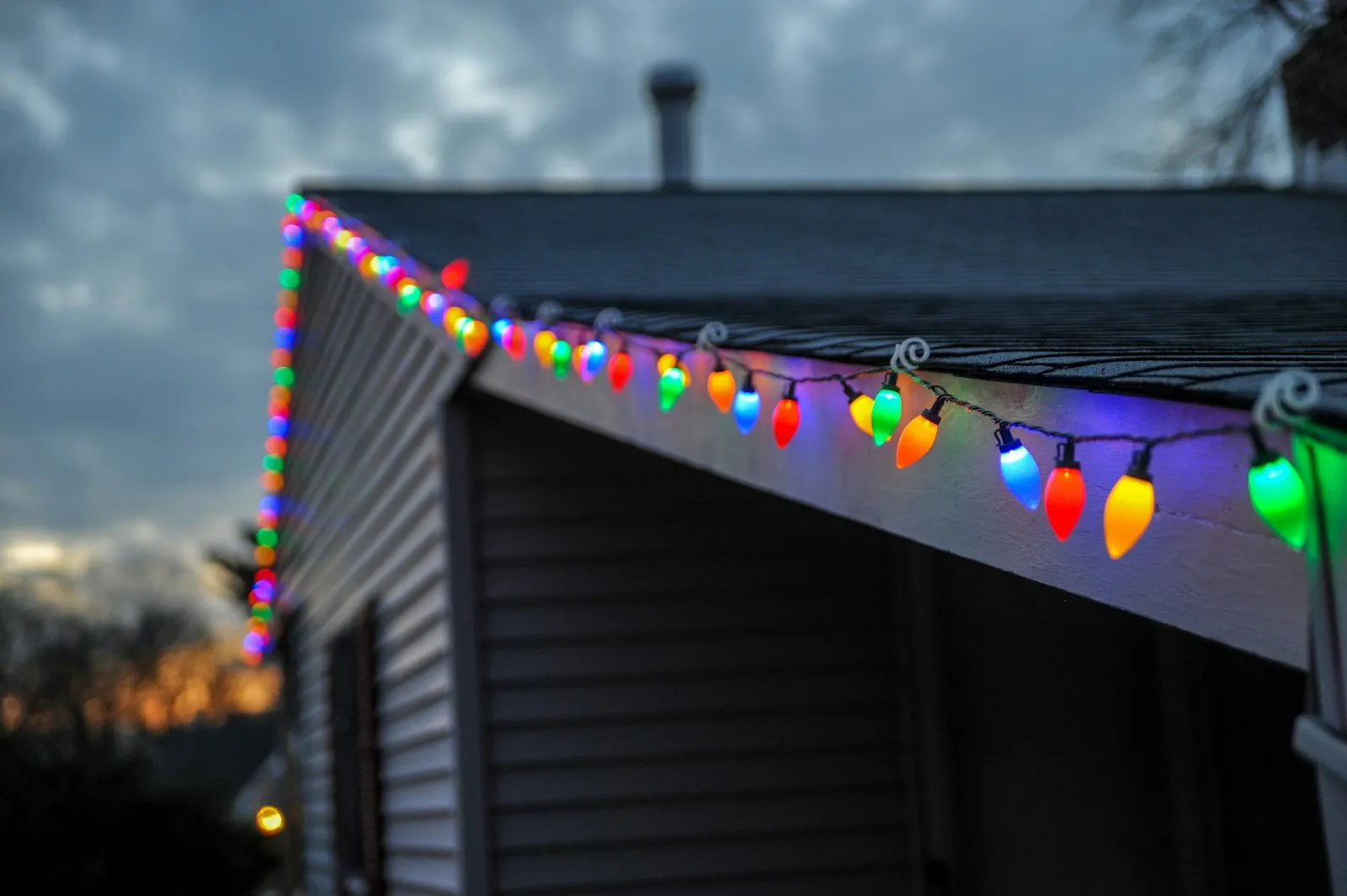 Colorful C9 Christmas bulbs clipped along the edge of a house roof