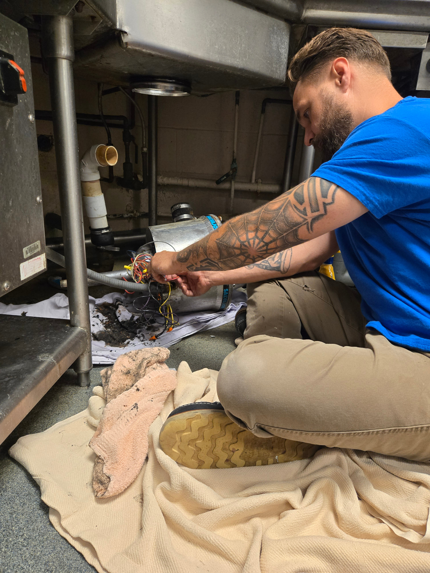 Justin replacing a garbage disposal under a stainless kitchen sink
