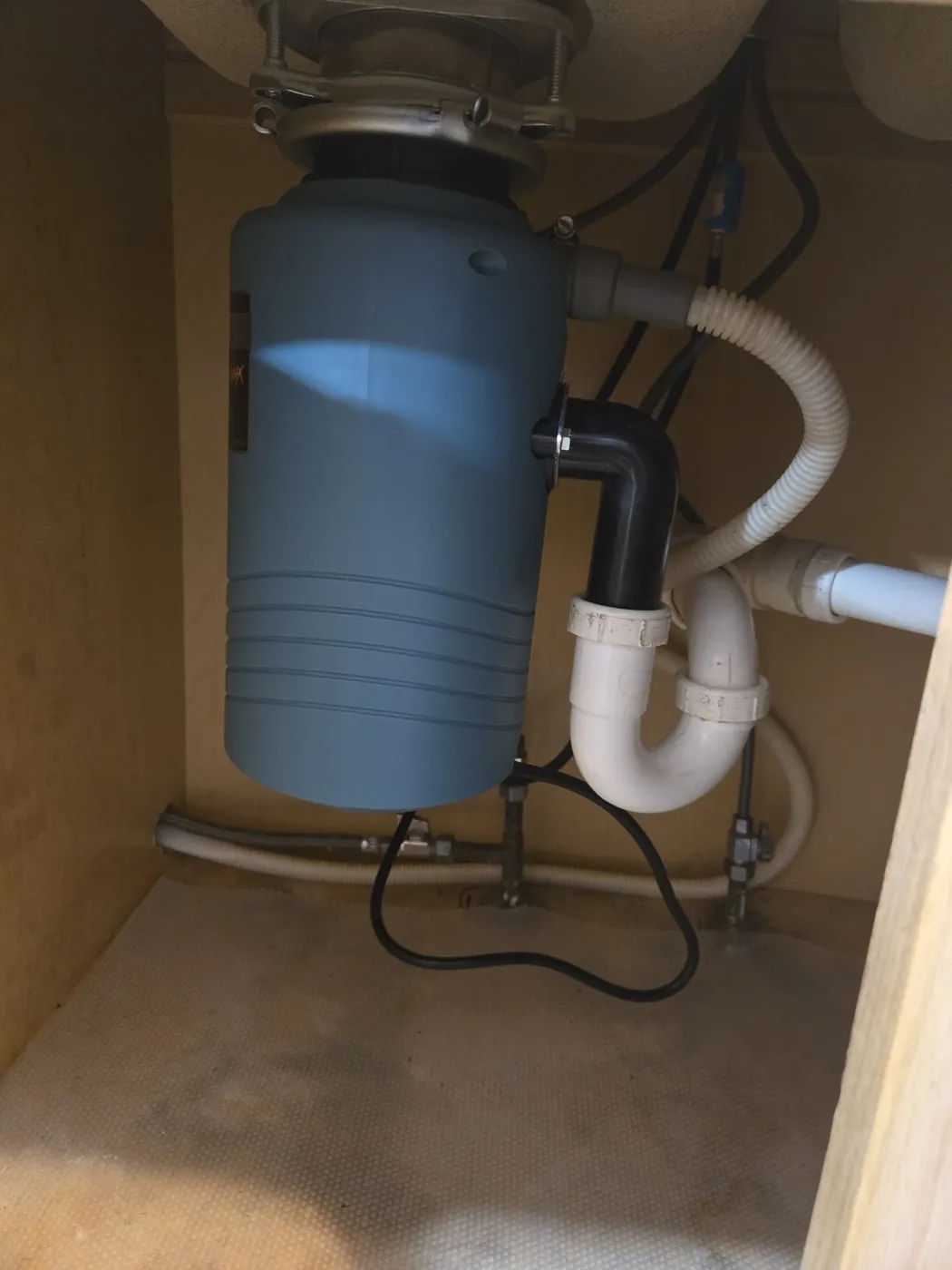 Garbage disposal and PVC drain trap installed under a kitchen sink