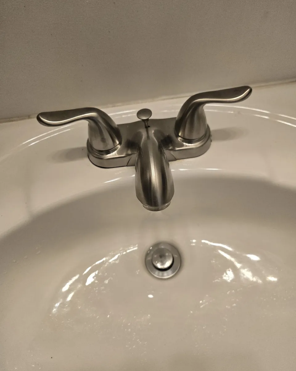 New brushed-nickel bathroom faucet installed on a white sink