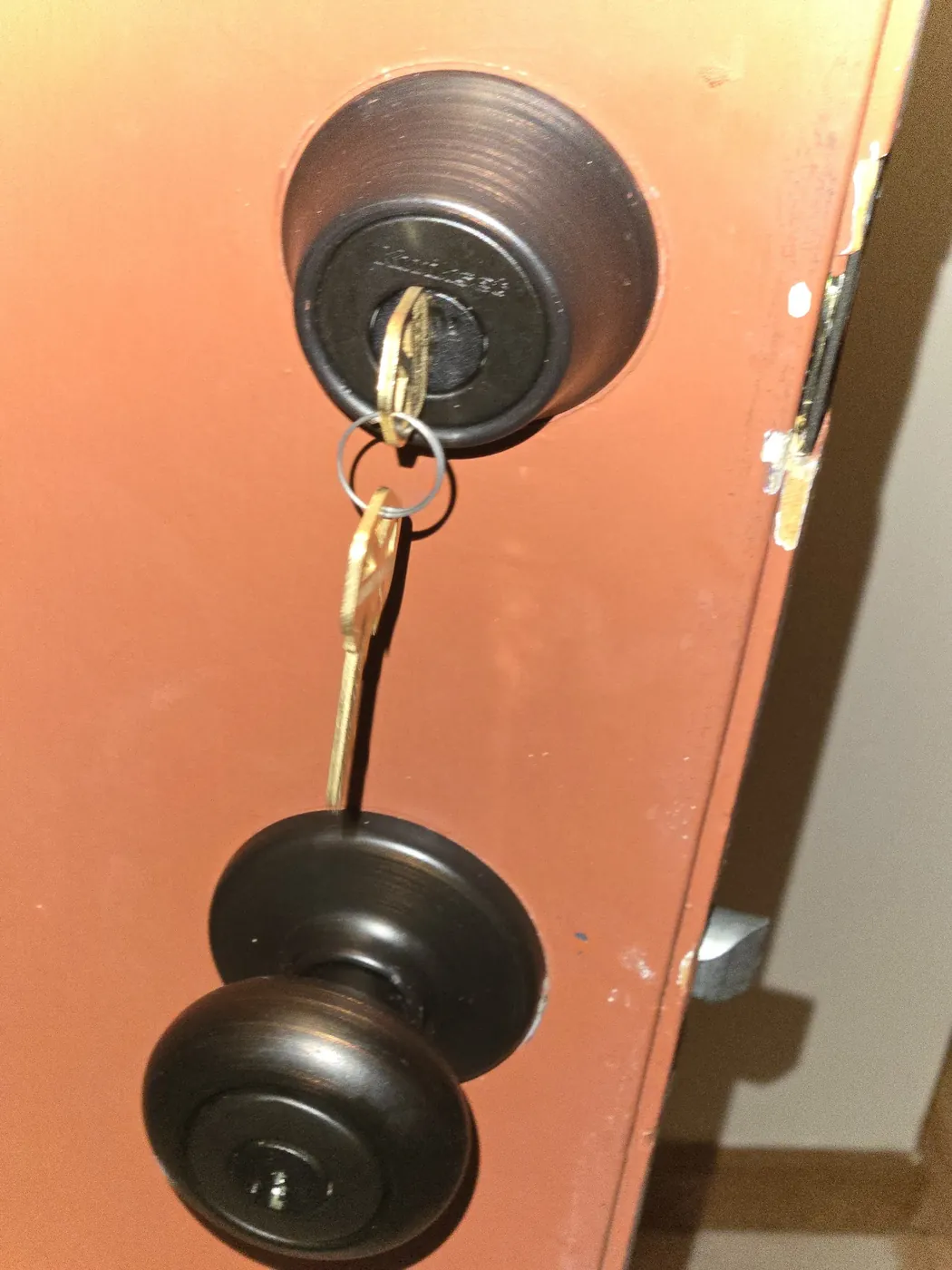 New bronze deadbolt and doorknob on a front door with keys in the lock