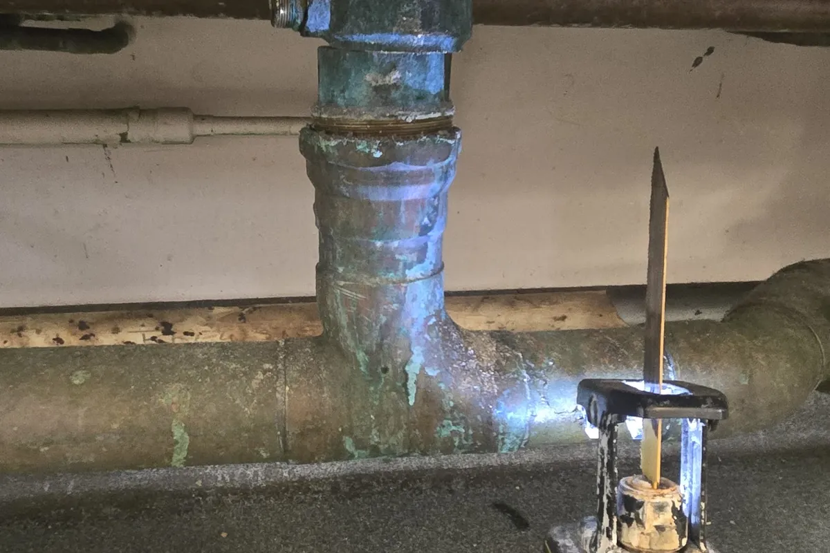 Corroded drain line under a sink being cut out for replacement