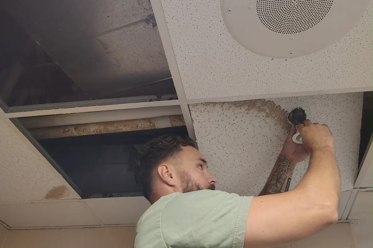 Justin fitting a new ceiling tile during a commercial repair