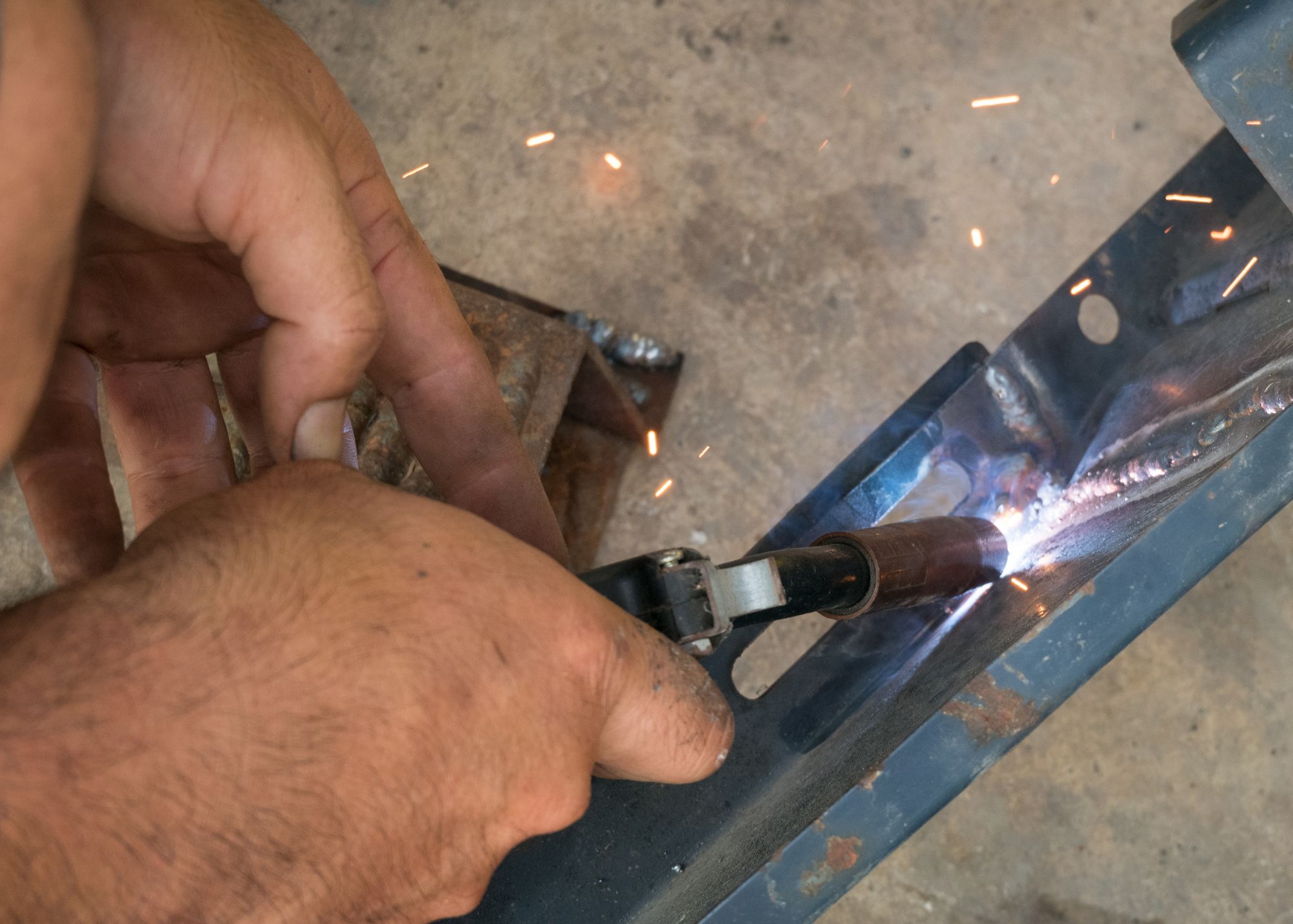 Close-up of a welding repair with sparks on a metal bracket