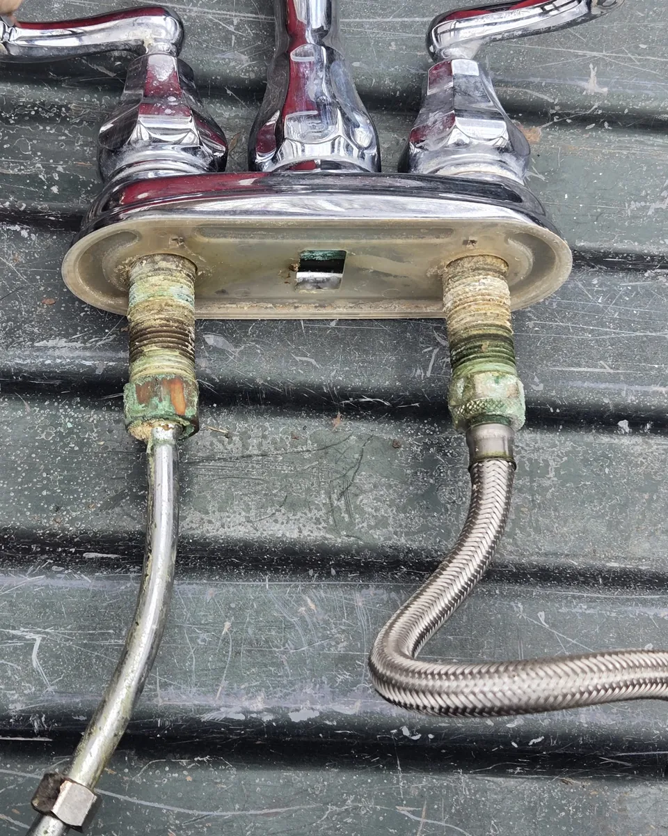 Old two-handle faucet removed with its supply lines